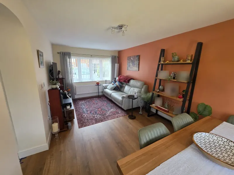 Garage converted to a living room with orange feature wall and laminate floor (photo 1)