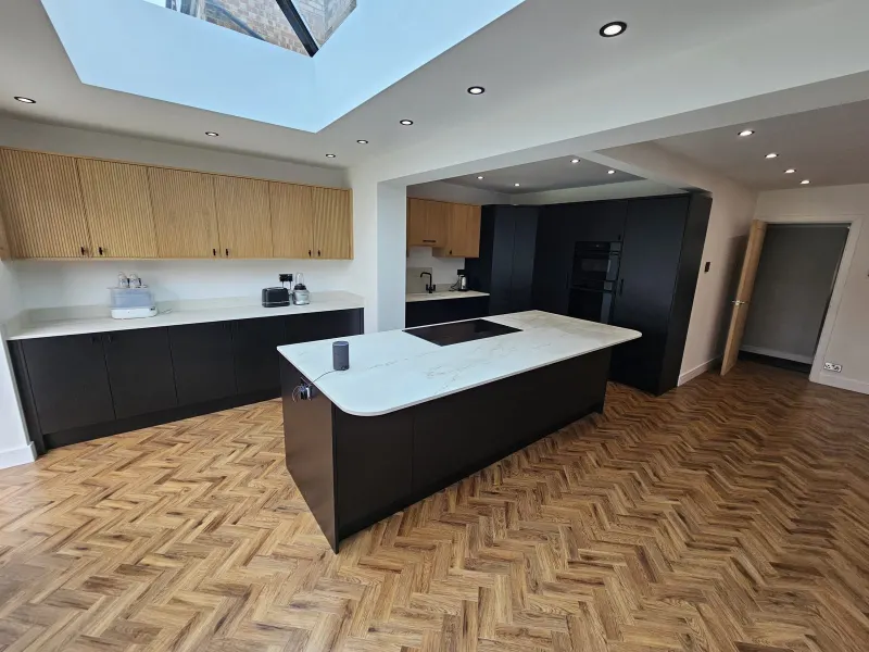 Kitchen extension with dark units, oak wall cabinets, white island and herringbone floor (photo 1)
